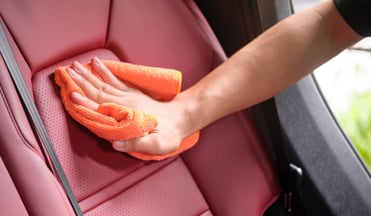 Asiento de cuero de vehículo recibe limpieza con trapo de microfibra